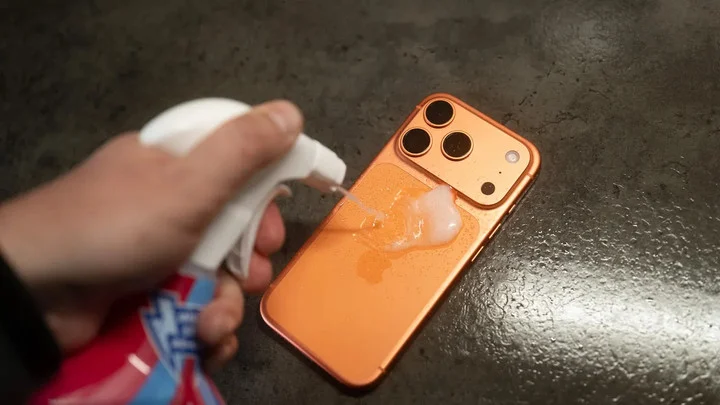 オレンジ色のiPhoneへ洗浄剤をかける変色テスト